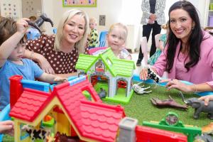 Image of 4 people sitting playing – First Minister Michelle O’Neill and deputy First Minister Emma Little-Pengelly pictured playing with children during their visit to Kids Korner Day Nursery in Belfast.